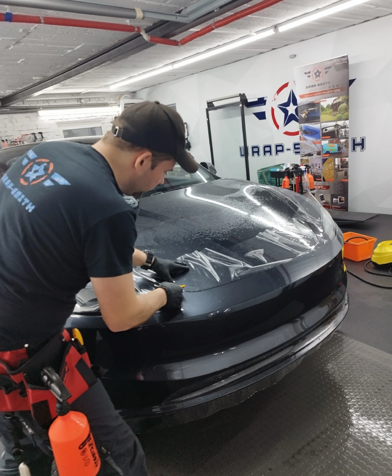 mężczyzna nakładający folię na samochód